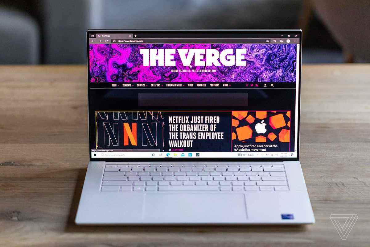 Ahşap bir masanın üzerinde önden görülen Dell XPS 15.  Ekranda The Verge ana sayfası görüntülenir.