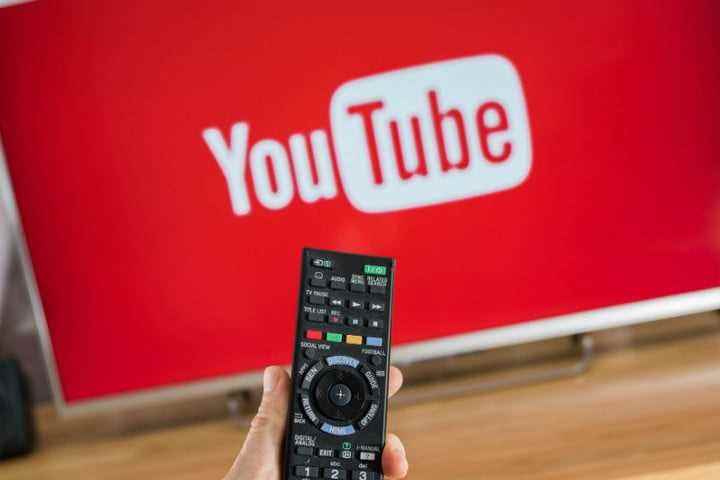 YouTube çalışırken uzaktan kumandayı TV'ye doğrultmuş bir kişi.