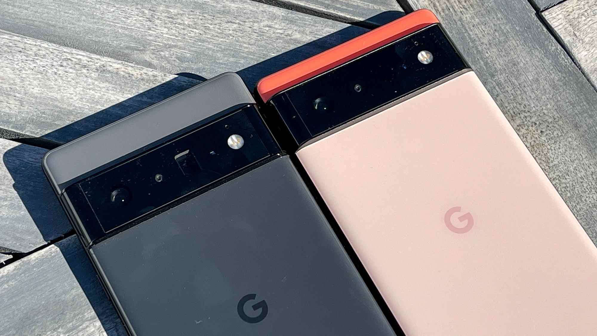 Google Pixel 6 Pro (siyah) ve Google Pixel 6 (mercan) ahşap zemin üzerine yan yana yerleştirilmiş