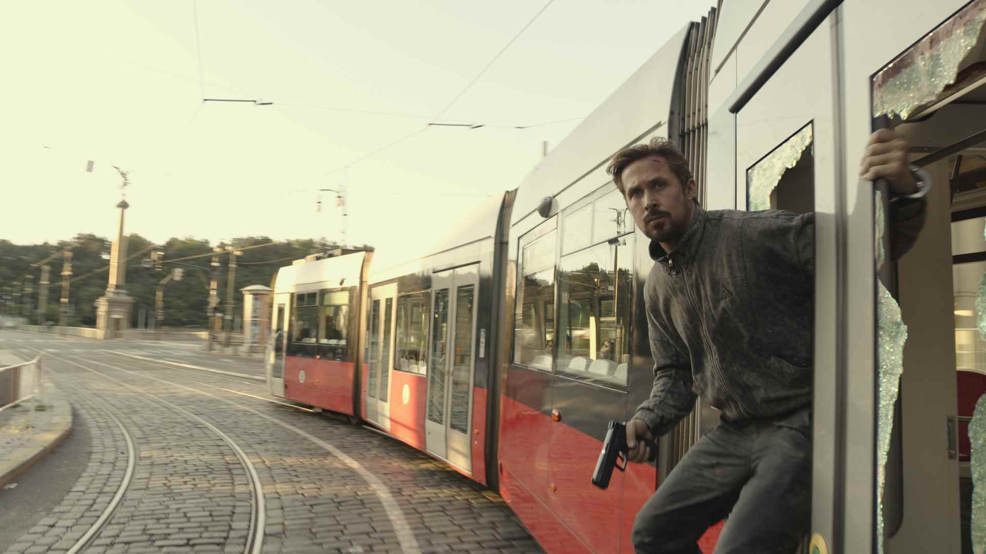 Ryan Gosling'in Sierra Six'i, Gri Adam'da elinde silahla bir trenin yanına asılıyor