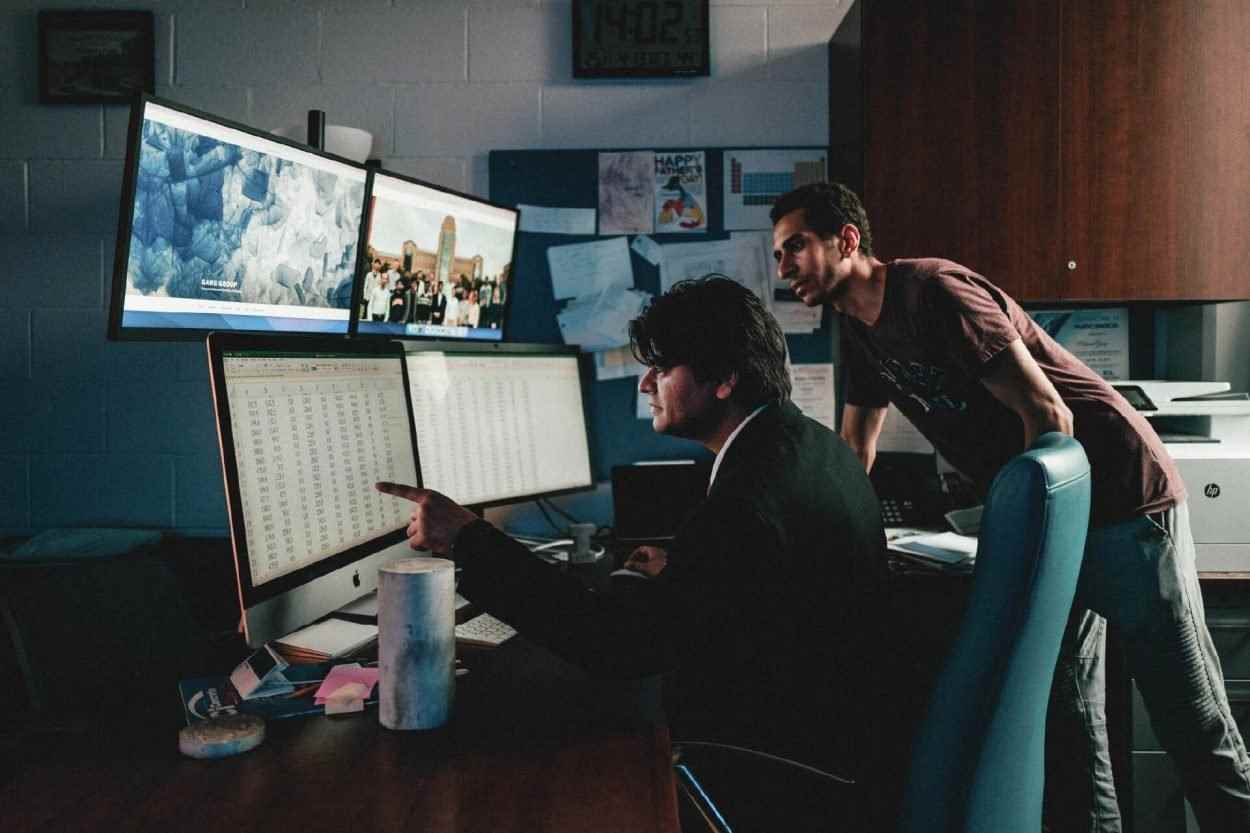 Birkaç bilgisayar ekranının önünde çalışan iki kişi