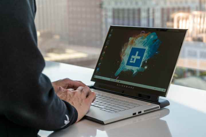 Bir kişi masa başında Alienware M15 yazıyor.