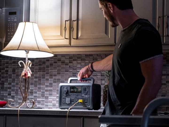 Bir adam, bir Bluetti EB3A ile elektrik kesintisi sırasında mutfakta bir lambaya güç veriyor.