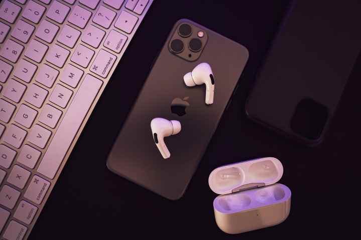 Yakınında açık şarj kutusu olan bir iPhone üzerinde duran AirPods Pro.