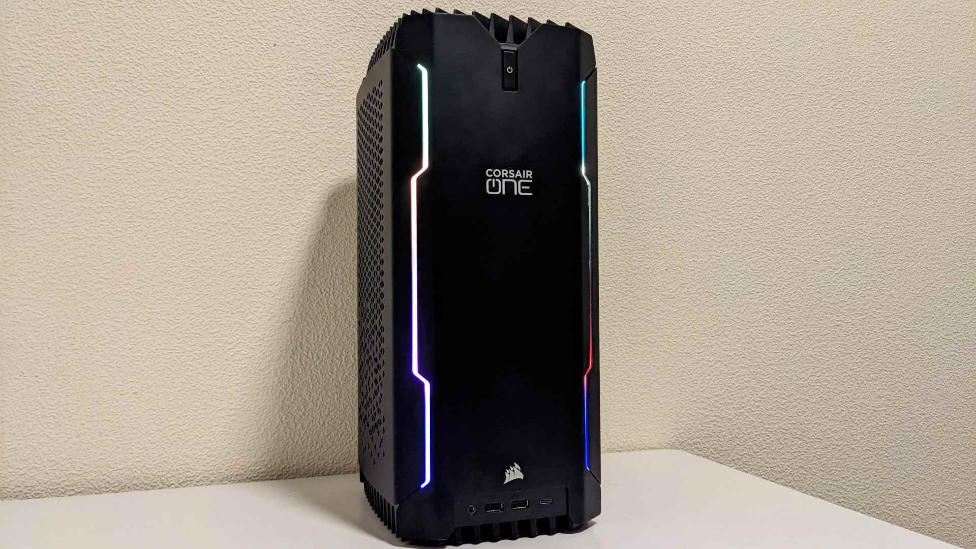 Corsair One i300 oyun bilgisayarı krem ​​arka planı olan beyaz bir masanın üzerinde duruyor