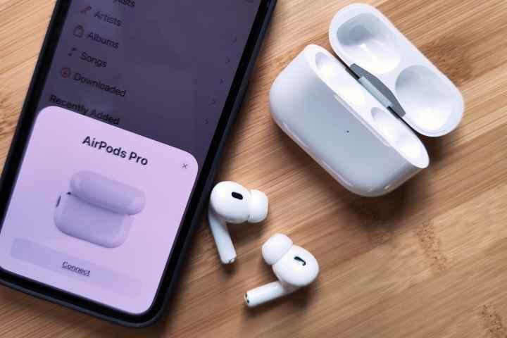 iPhone 14'ün yanında oturan Apple AirPods Pro 2 ve şarj kutusu.