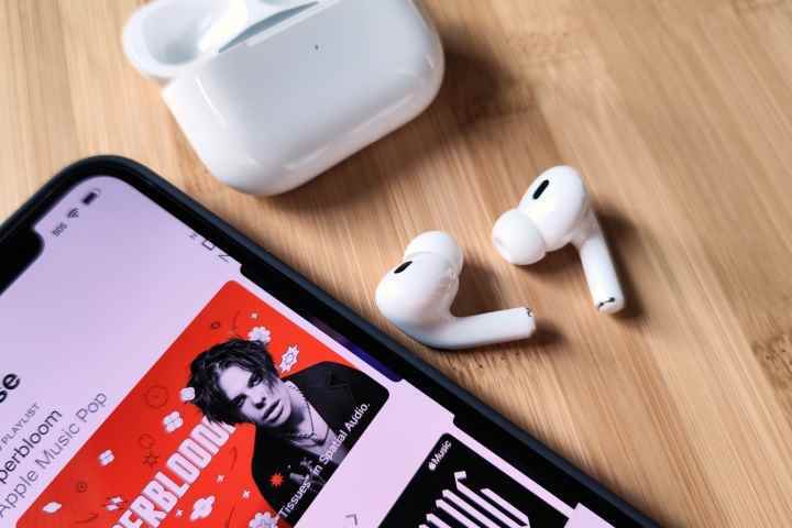 iPhone 14'ün yanında oturan Apple AirPods Pro 2 ve şarj kutusu.