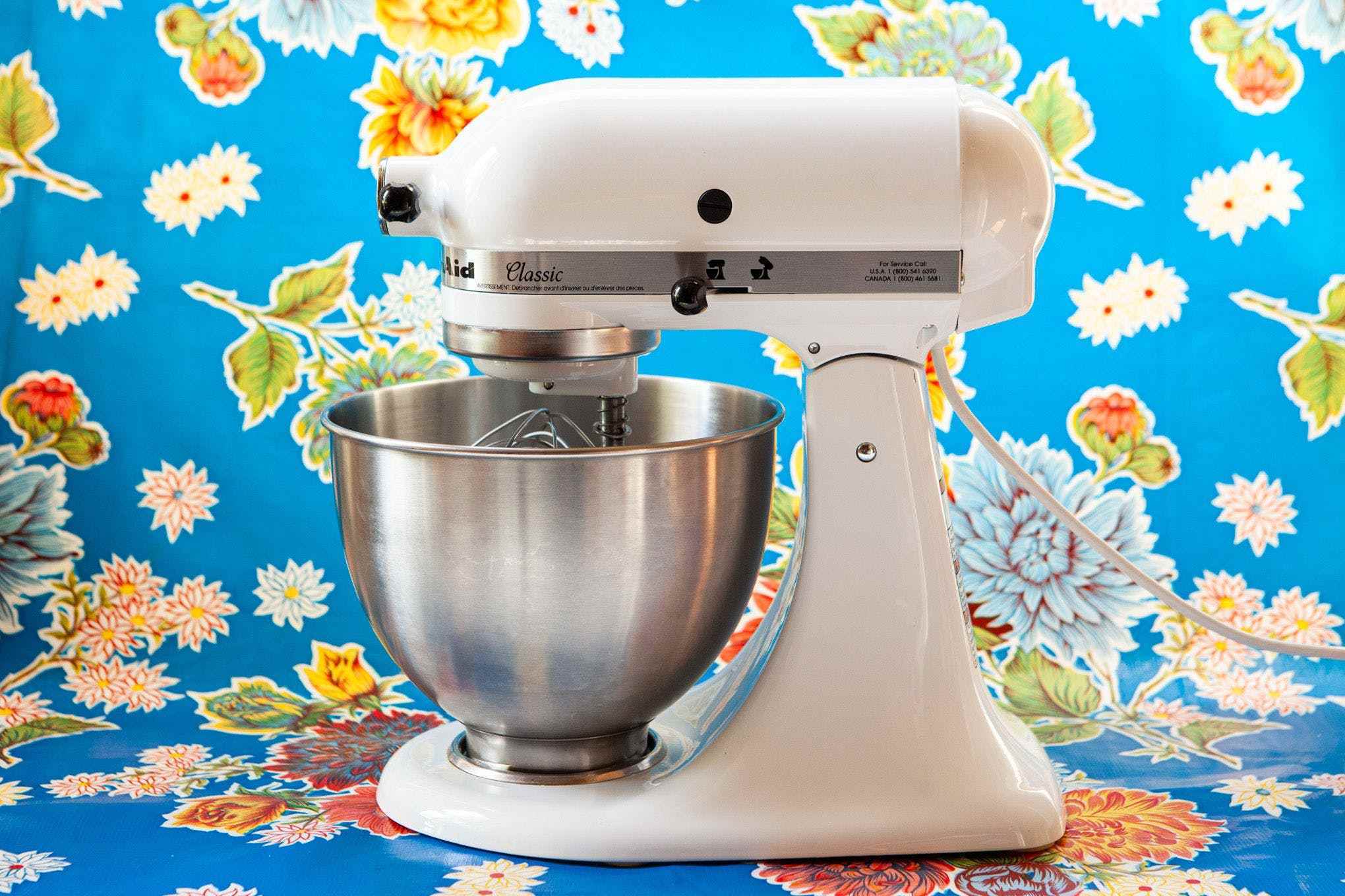 Mavi çiçekli bir arka planın önünde bir KitchenAid stand mikserinin fotoğrafı.