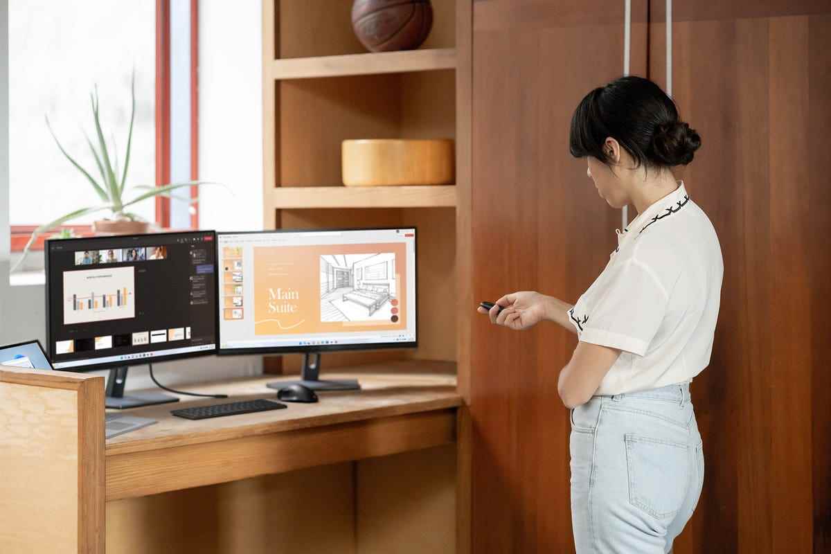 İki monitörün önünde Microsoft Presenter+ işaretçisini kullanan kadın