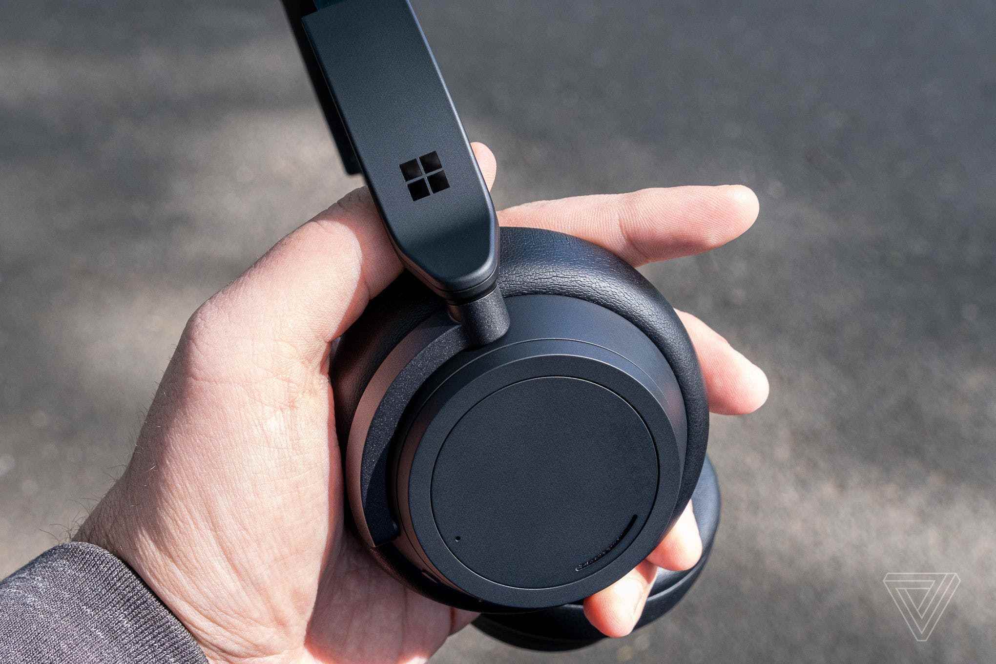 İnceleyenin elinde gösterilen mat siyah Surface Headphones 2.