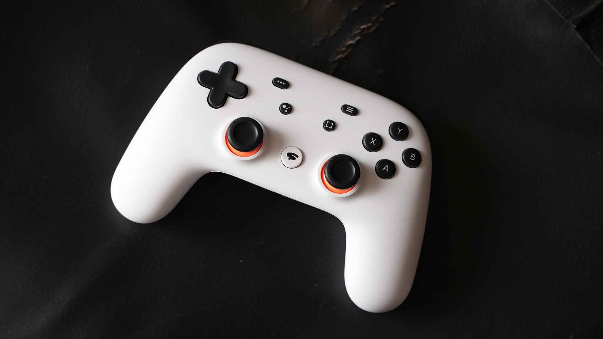 Siyah bir yüzey üzerinde duran Google Stadia kumandası