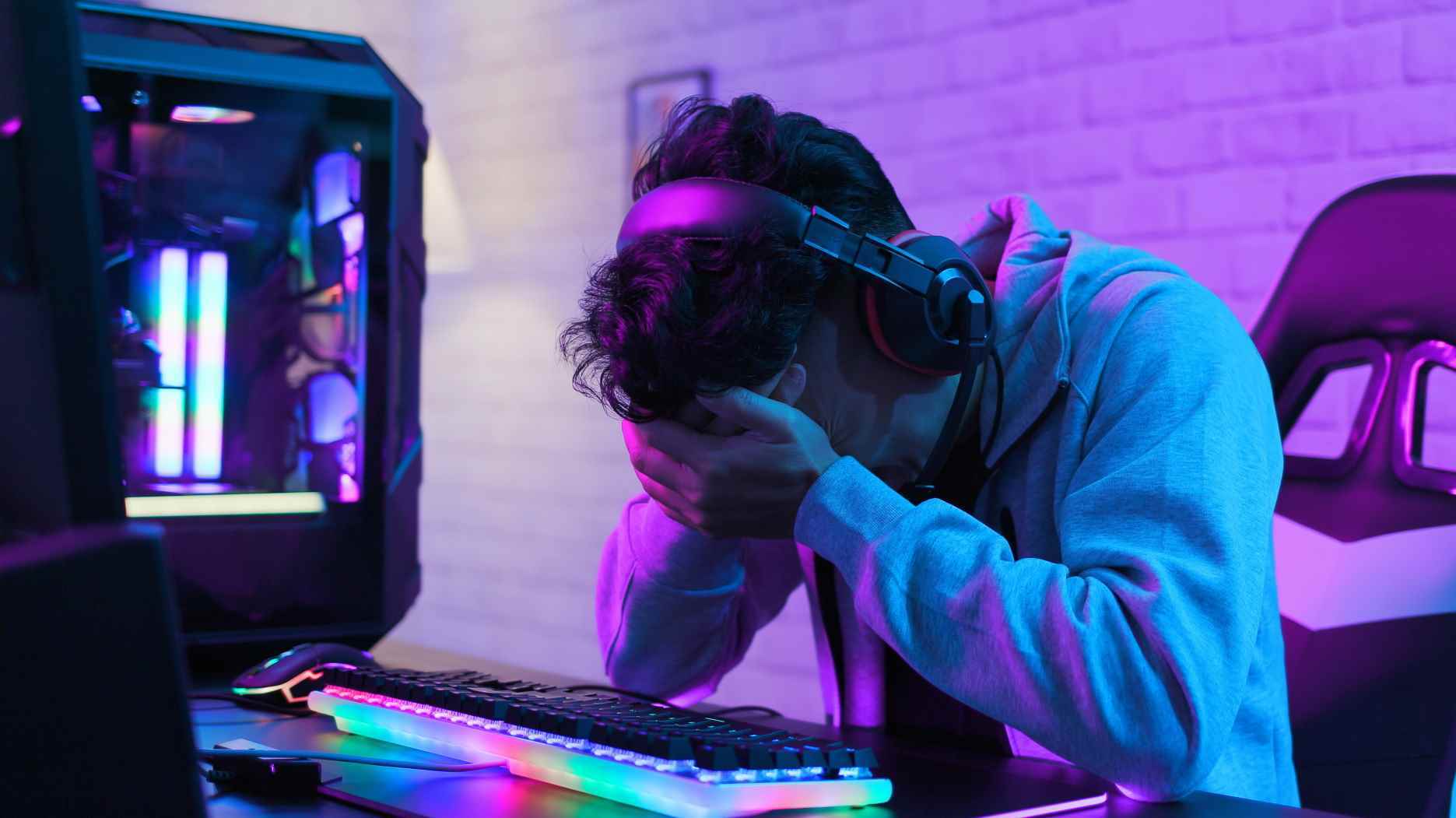 Bilgisayarının başında kafası ellerinde olan üzgün bilgisayar oyuncusu
