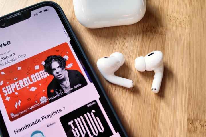 Apple AirPods Pro 2, iPhone 14'ün yanında ve şarj kutusu.