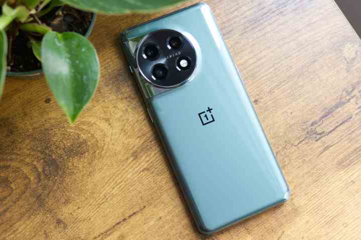 OnePlus 11 (yeşil), masanın üzerinde yüzüstü yatıyor.