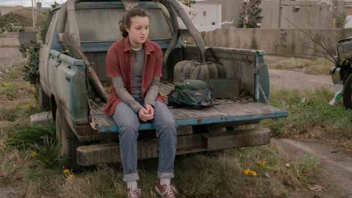 Ellie, The Last of Us'ta bir kamyonun üzerinde oturuyor.