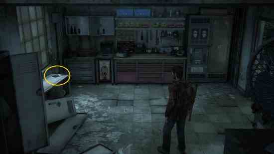 The Last of Us eğitim kılavuzları: Bir adam karanlık bir odadaki tezgahın üzerinde bir kitap bulur.