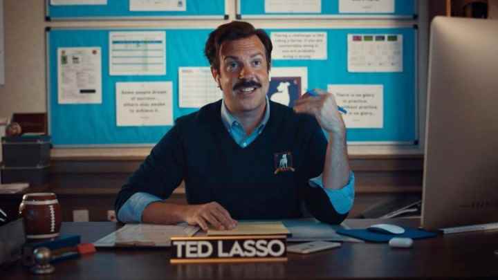 Ted, Ted Lasso'daki masasında oturuyor.