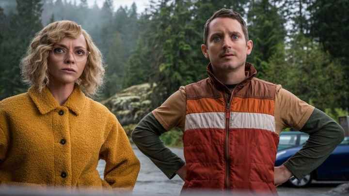 Christina Ricci ve Elijah Wood elleri belinde durup Yellowjackets'ten bir sahnede bir şeye bakıyorlar.