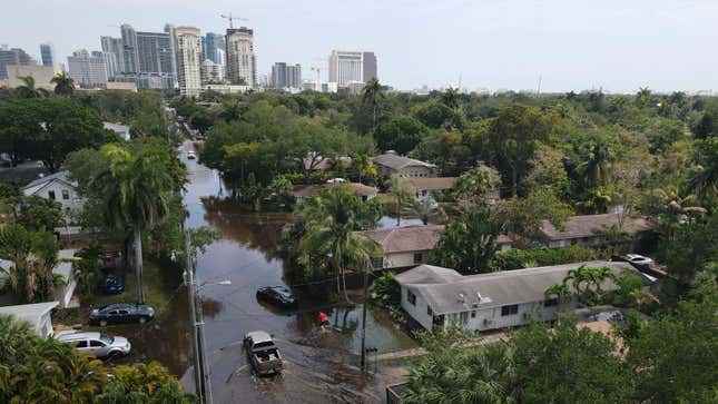 Kamyonlar ve bir sakin, 13 Nisan 2023'te Florida, Fort Lauderdale'in Sailboat Bend semtinde çekilen sel sularında ilerliyor.