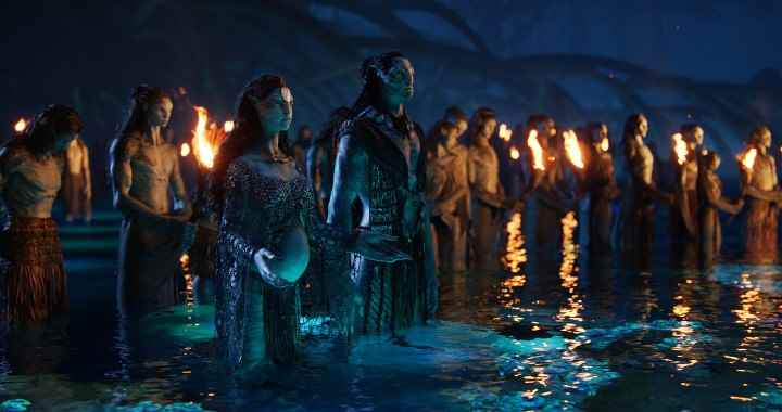 Avatar: The Way of Water'dan bir sahnede bir grup Na'vi suda yas tutarken etraflarında alevler var.