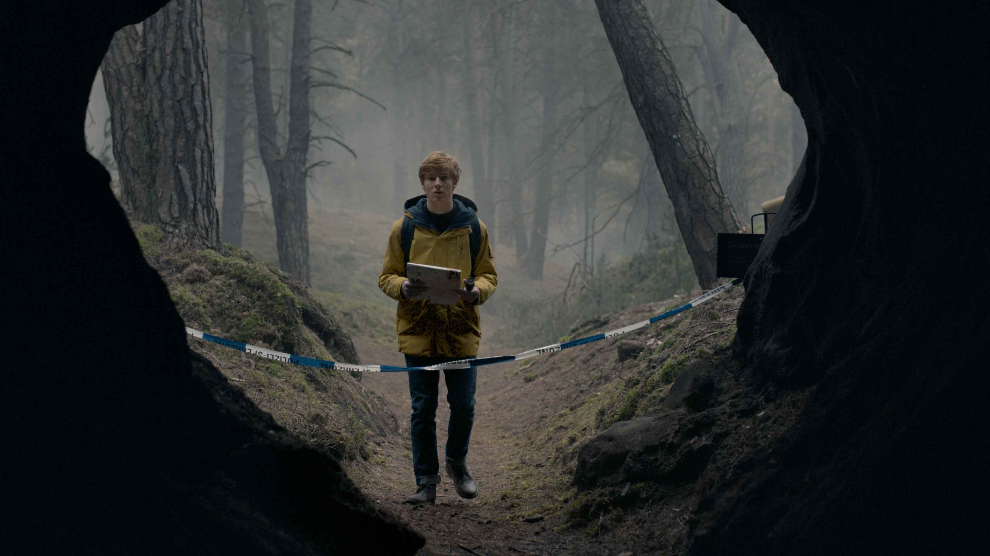 Jonas Kahnwald (Louis Hofmann), Netflix'in Dark'ında uyarı bandıyla kapatılmış bir mağaraya bakıyor.