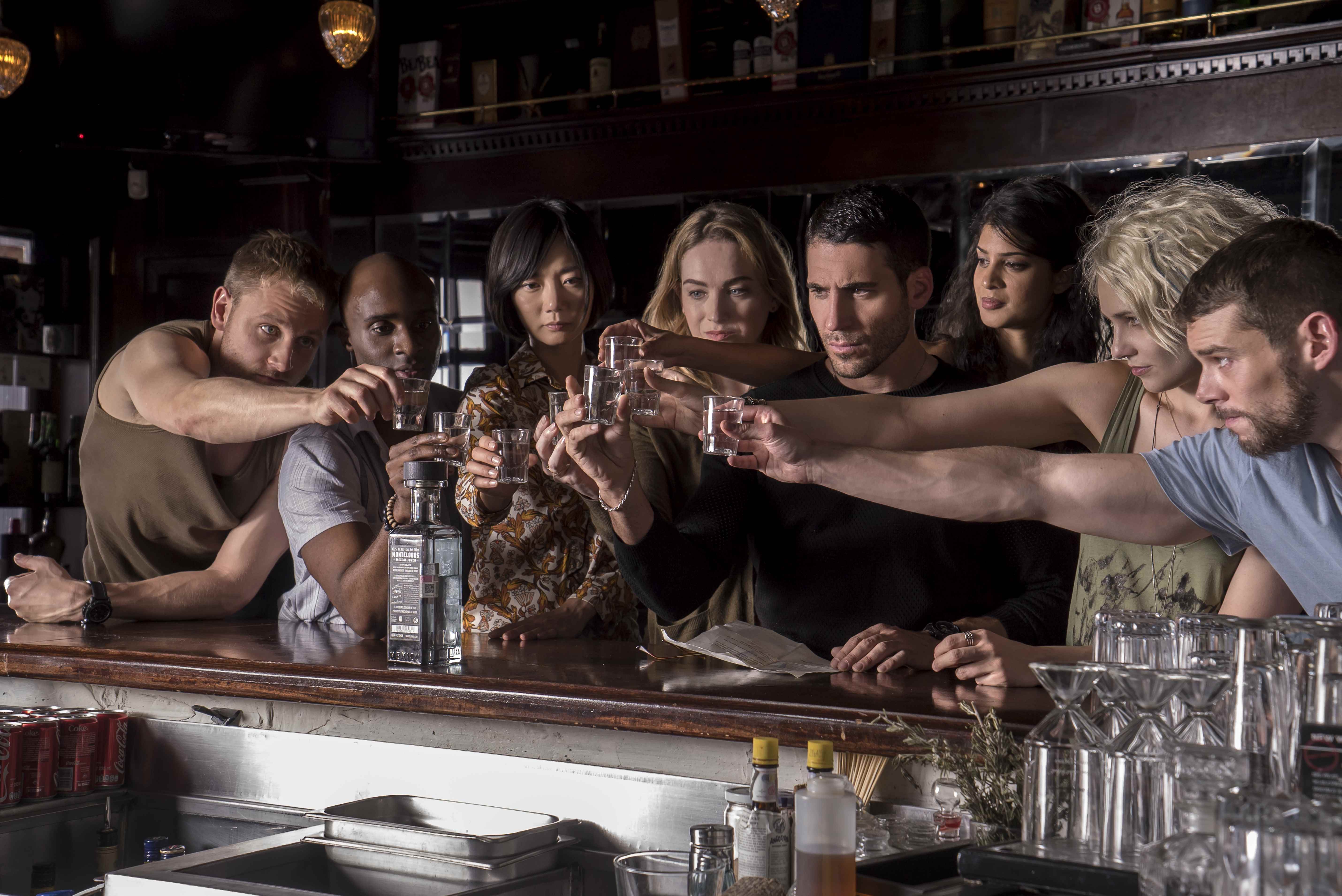 (Soldan sağa) Wolfgang (Max Riemelt), Capheus (Toby Onwumere), Sun (Bae Doona), Nomi (Jamie Clayton), Lito (Miguel Angel Silvestre), Kala (Tina Desai), Riley (Tuppence Middleton) karakterleri ve Will (Brian J Smith), Sense8'de kadeh kaldırmak için kadehlerini kaldırıyorlar.