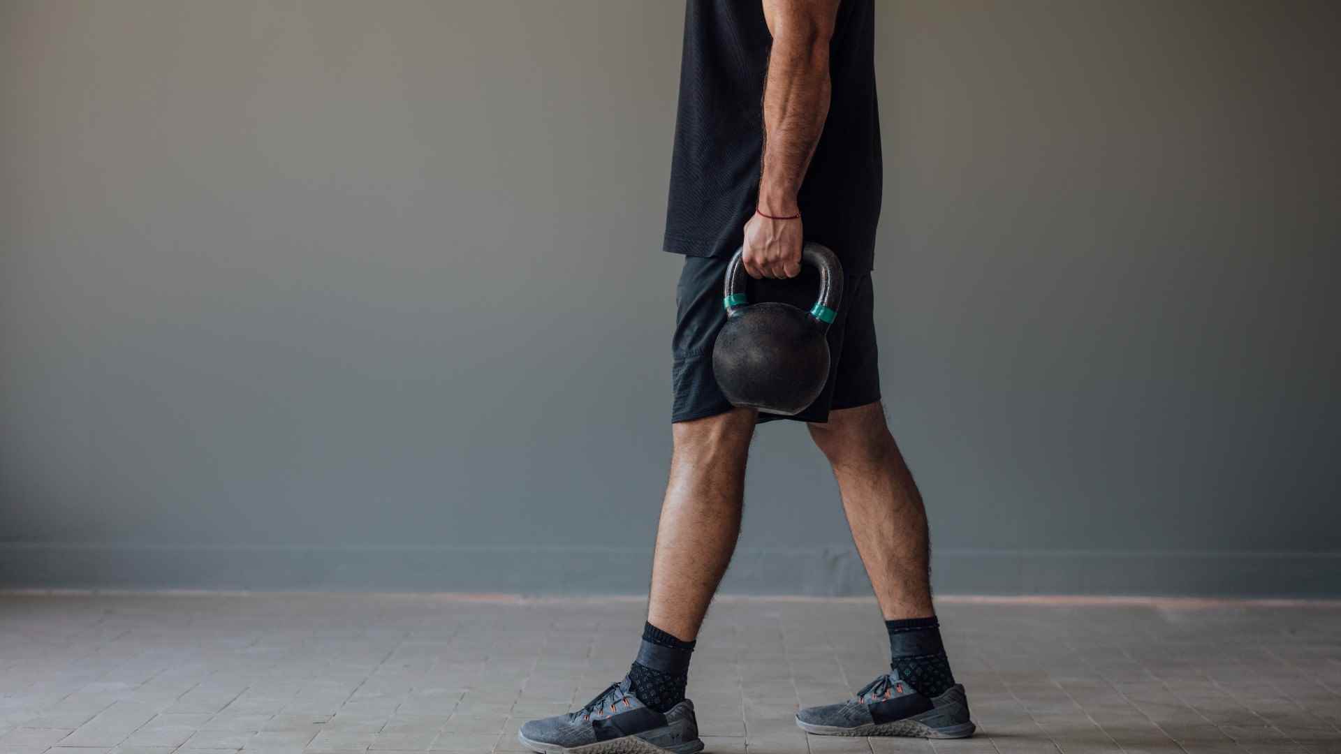 Çiftçi yürüyüşünde elinde iki kettlebell ile yürüyen adam