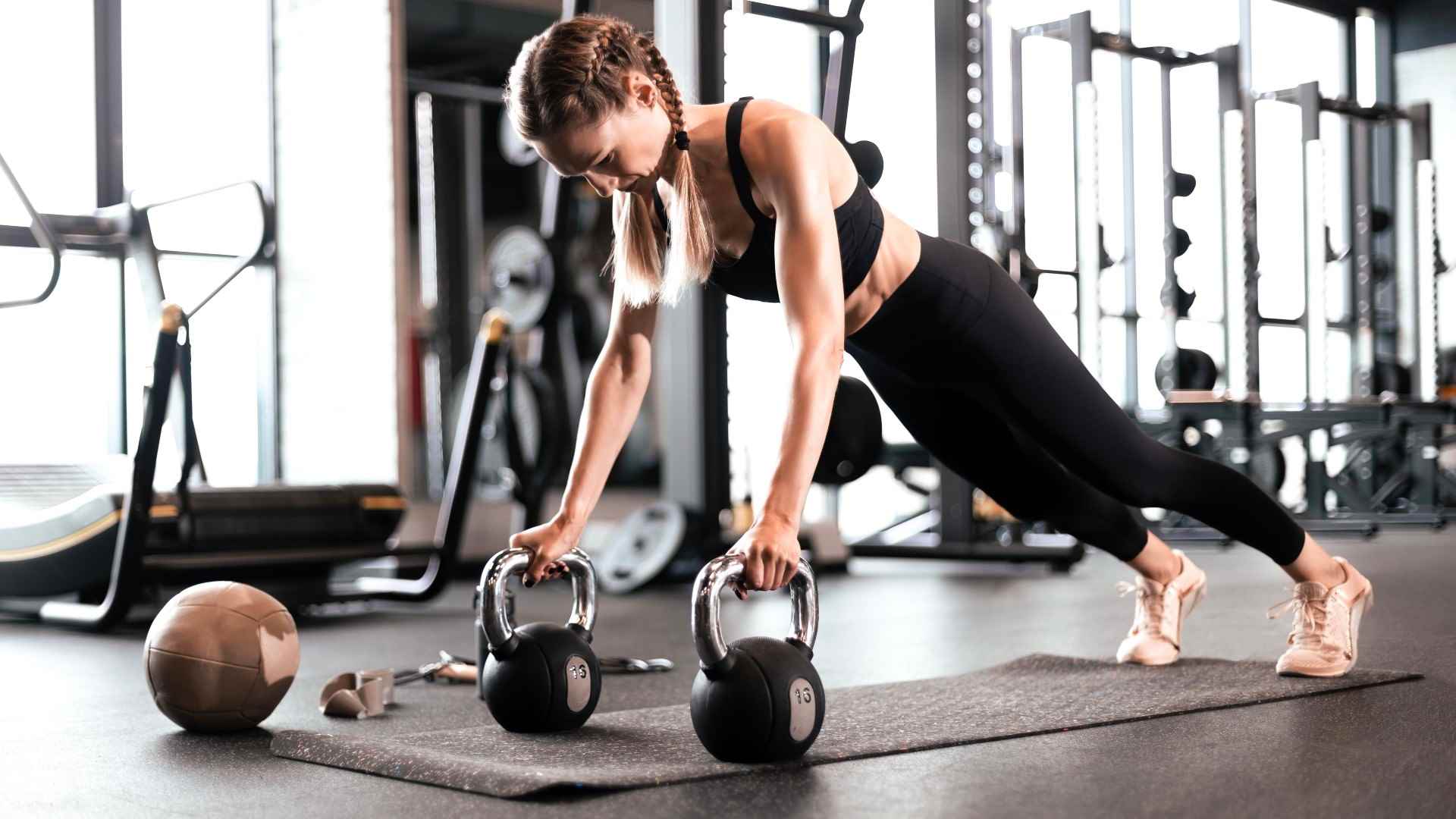 Kadın iki kettlebell kullanarak dönek kürek çekiyor