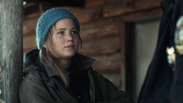 Winter's Bone'da tahta bir sütuna yaslanan Ree Dolly rolünde Jennifer Lawrence.