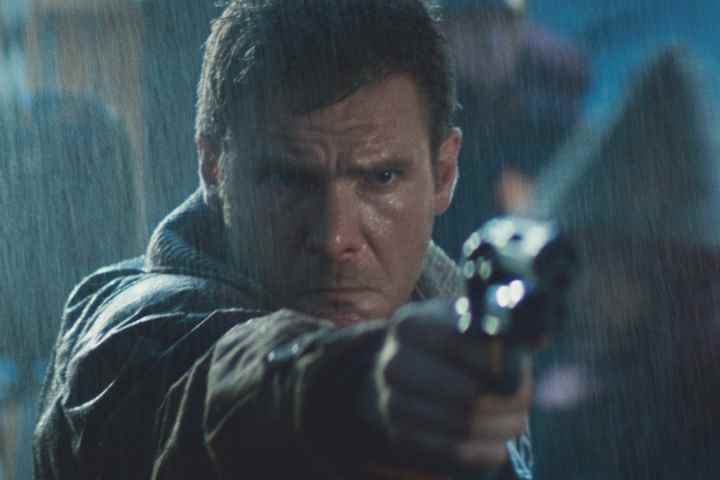 Harrison Ford, Blade Runner'da yağmurda silahını doğrultuyor.