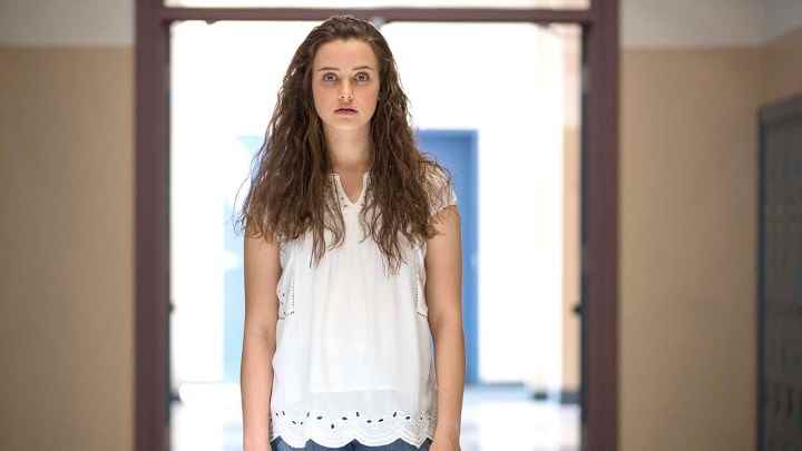 13 Reasons Why'dan Hannah beyaz bir gömlek giyiyor, arkasında beyaz bir ışıkla duruyor.