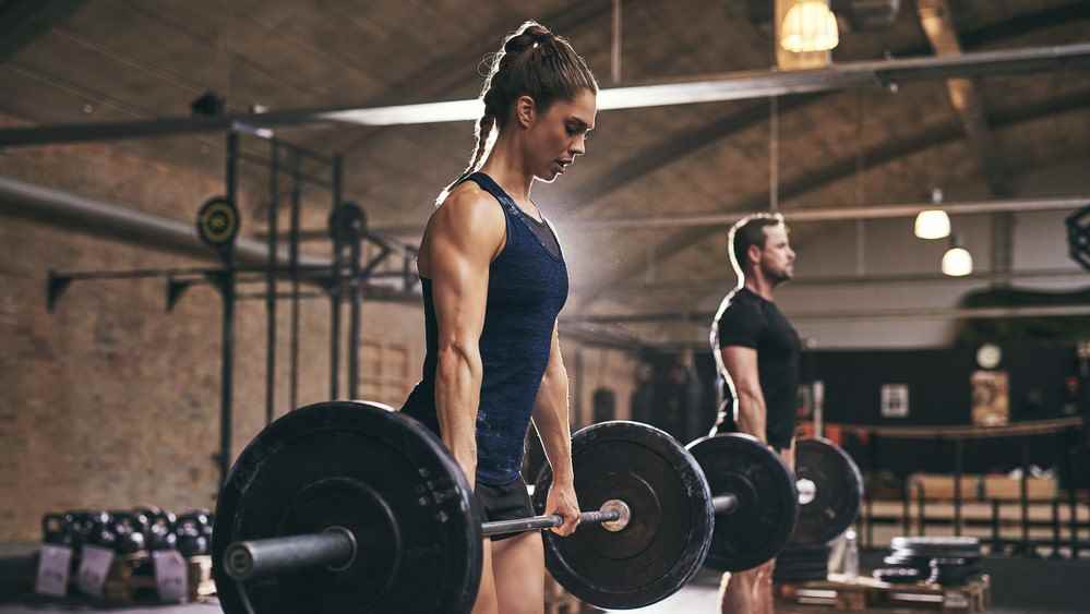 spor salonunda halter tutan bir erkek ve kadının fotoğrafı