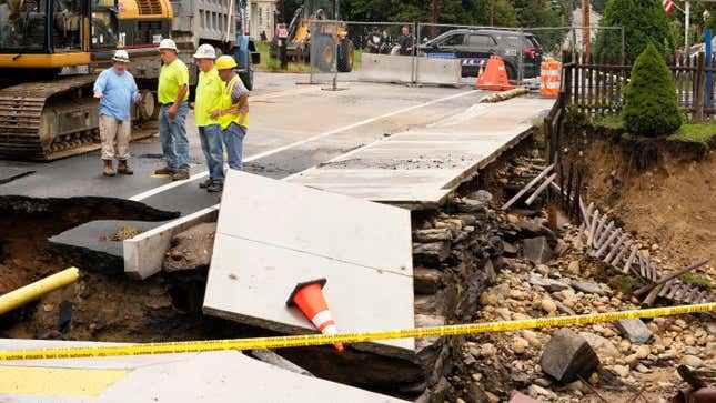 Bayındırlık işleri yetkilileri, 13 Eylül 2023'te Leominster, Massachusetts'te yakın zamanda yaşanan sel nedeniyle sular altında kalan yol ve ön bahçedeki hasarı inceliyor.