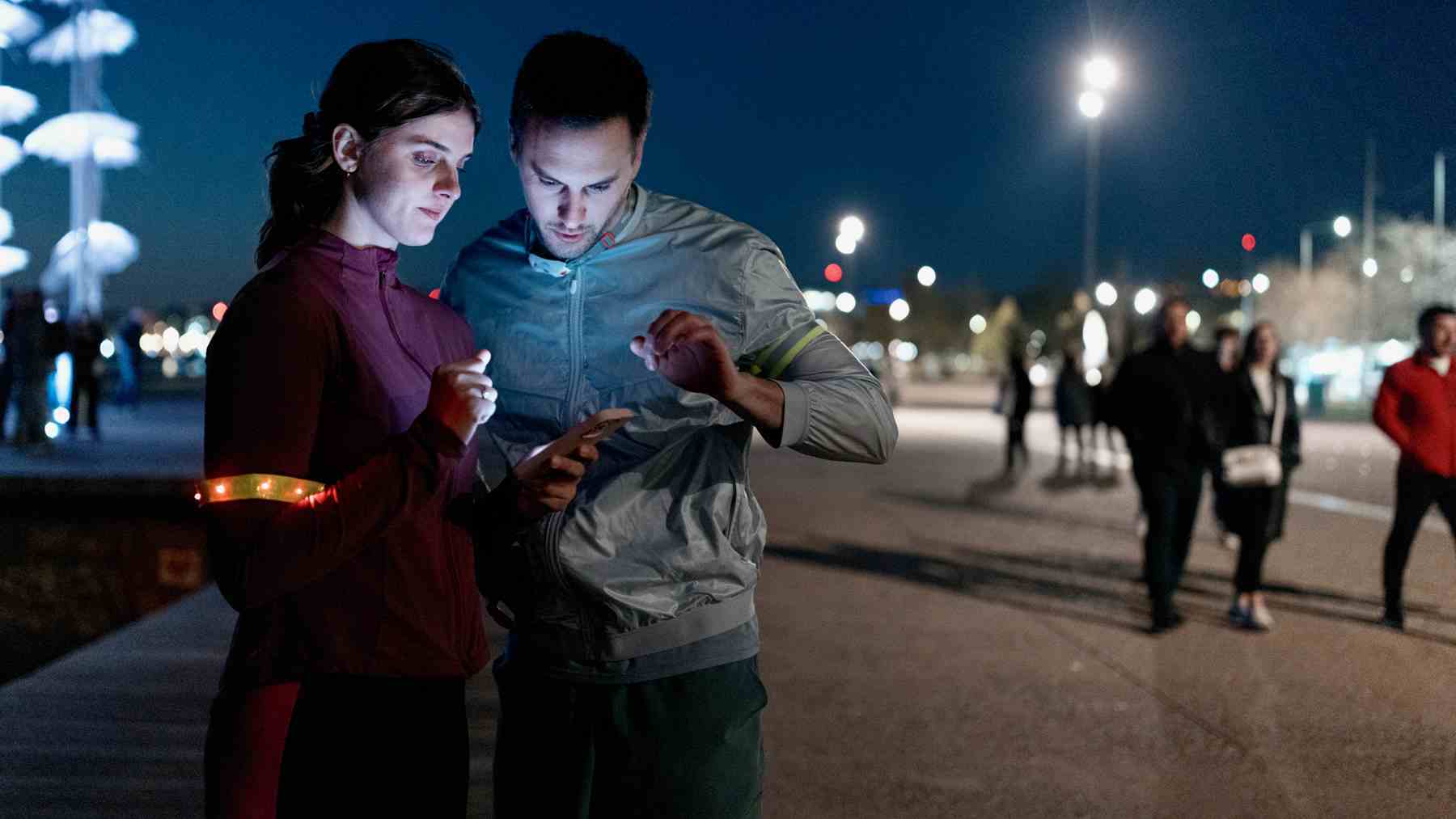 Koşunun ortasında telefonu kontrol etmek için duran kadın ve erkeğin fotoğrafı