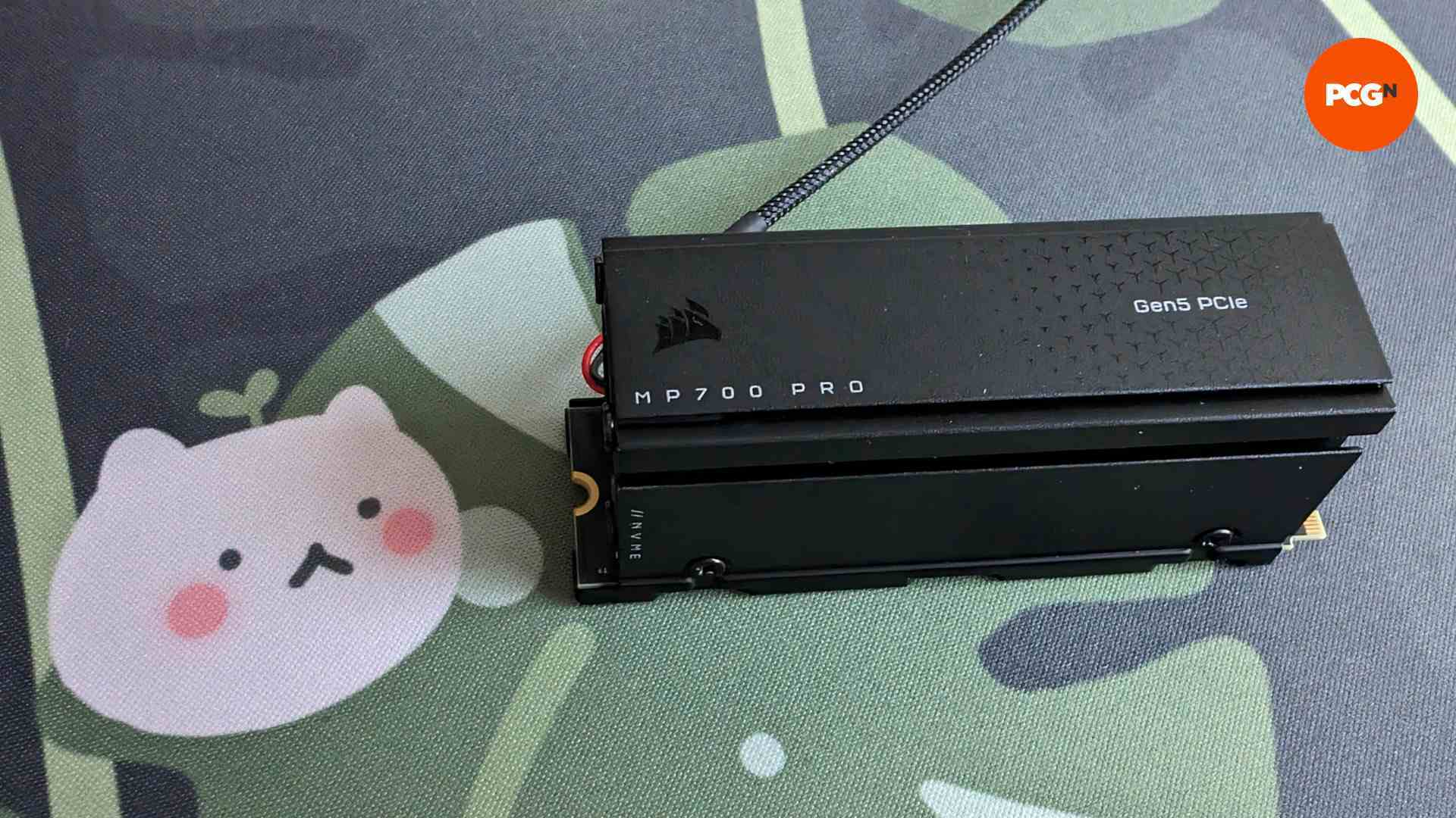 Yapraklı bir arka plana sahip Corsair MP700 Pro, küçük beyaz kedi benzeri bir karaktere sahiptir (solda)