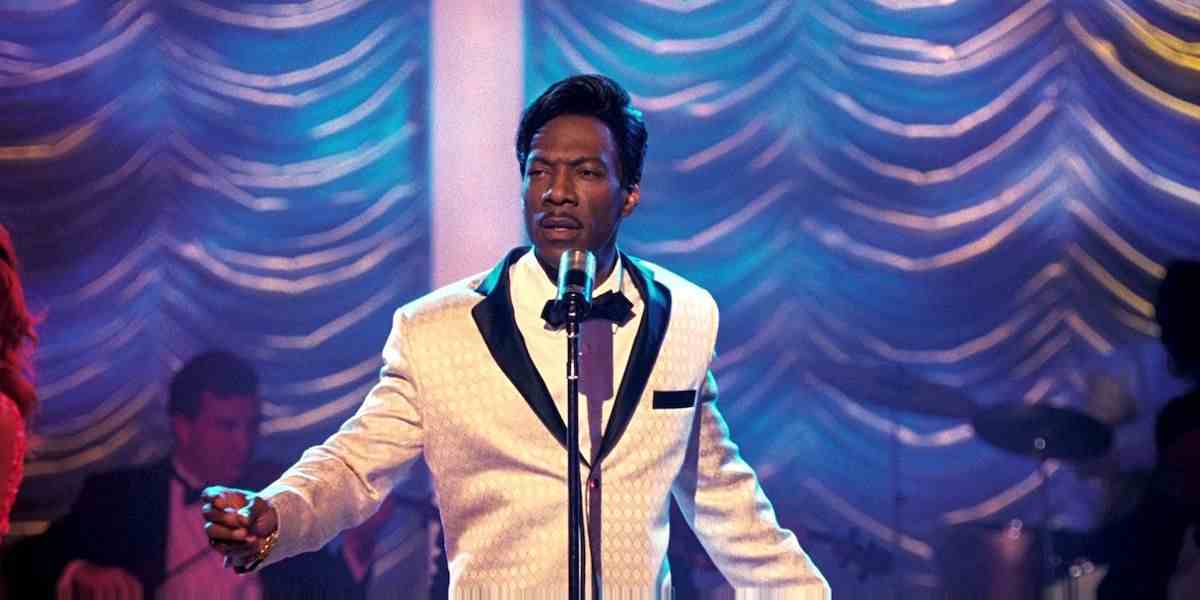 Dreamgirls'de beyaz bir takım elbise giyen ve mikrofona konuşan Eddie Murphy