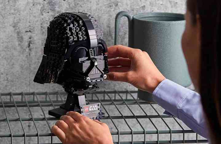 Bir kadın Lego Star Wars Dart Vader Kaskını rafa koyuyor.