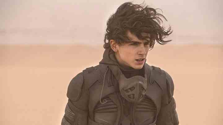 Timothy Chalamet çölde yürüyor, Dune'dan bir sahnede saçları uçuşuyor.