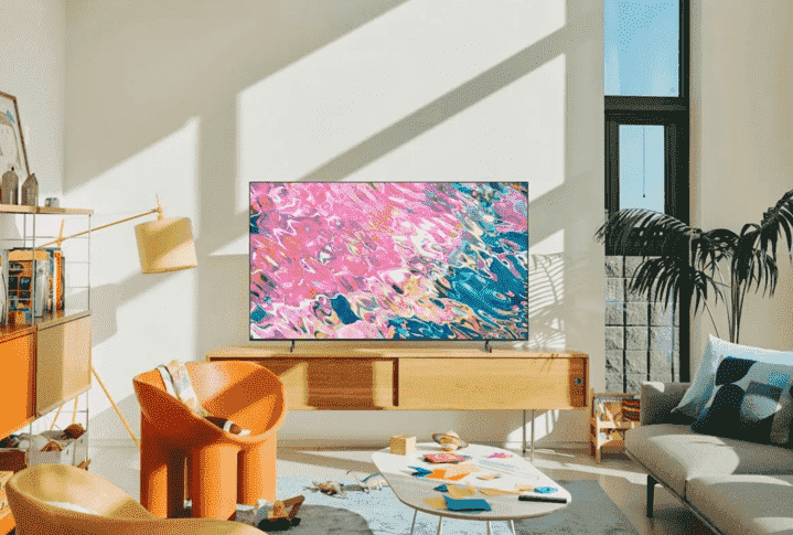 Samsung Q60B QLED Smart TV, oturma odasındaki medya dolabının üzerinde duruyor.