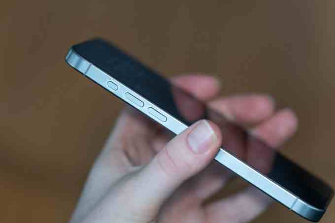 Doğal titanyum iPhone 15 Pro Max, tutuluyor, telefonun Aksiyon ve ses düğmeleri dahil yan tarafı gösteriliyor
