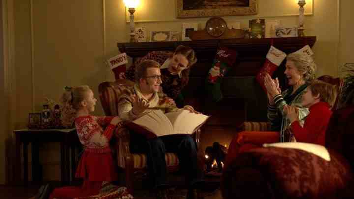 Bir aile ateşin etrafında oturuyor ve A Christmas Story Christmas filminden bir sahnede kitap okuyor.