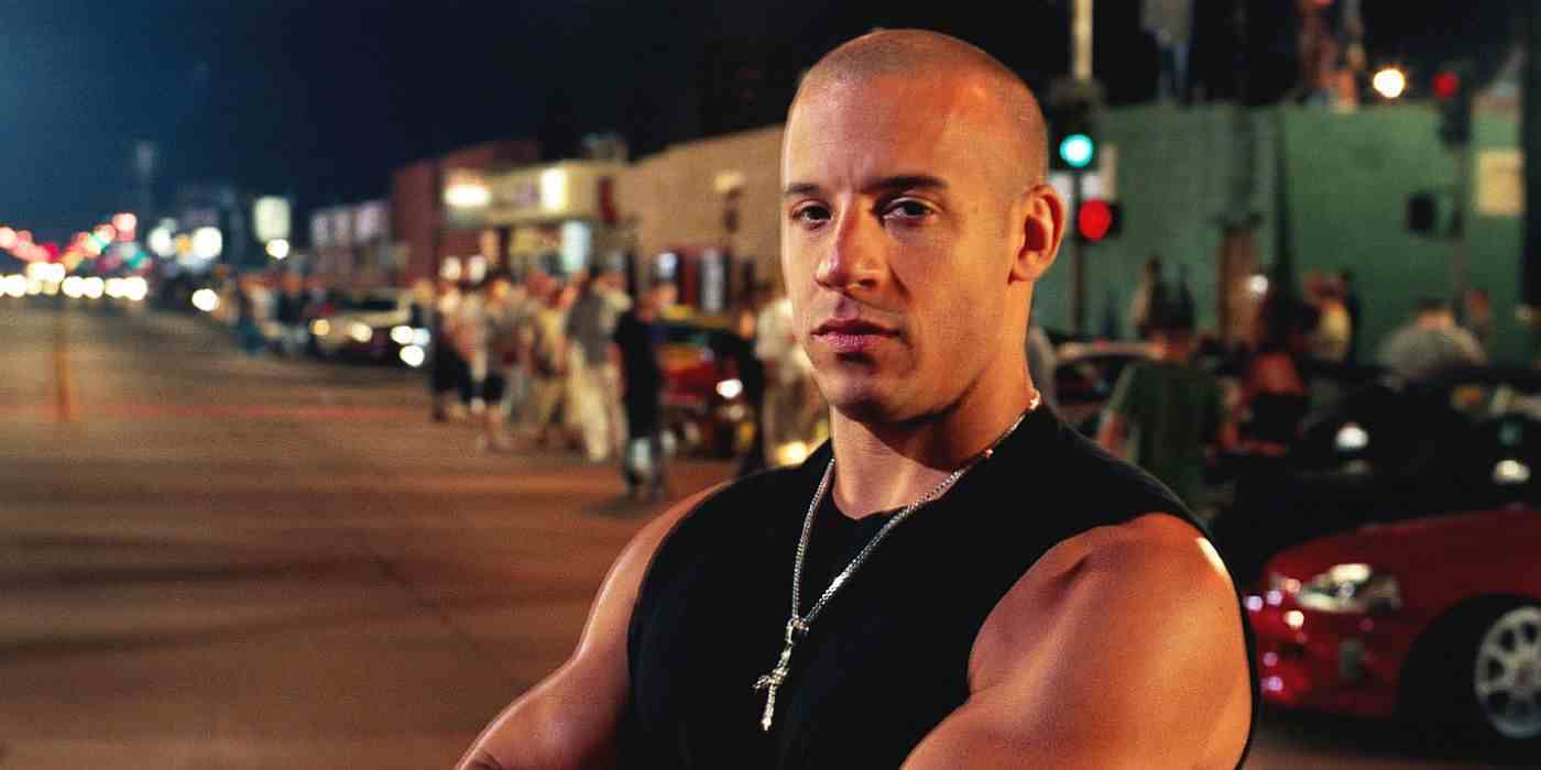 Dominic Toretto, Hızlı ve Öfkeli'de güçlendirilmiş arabalarla dolu bir caddenin önünde duruyor