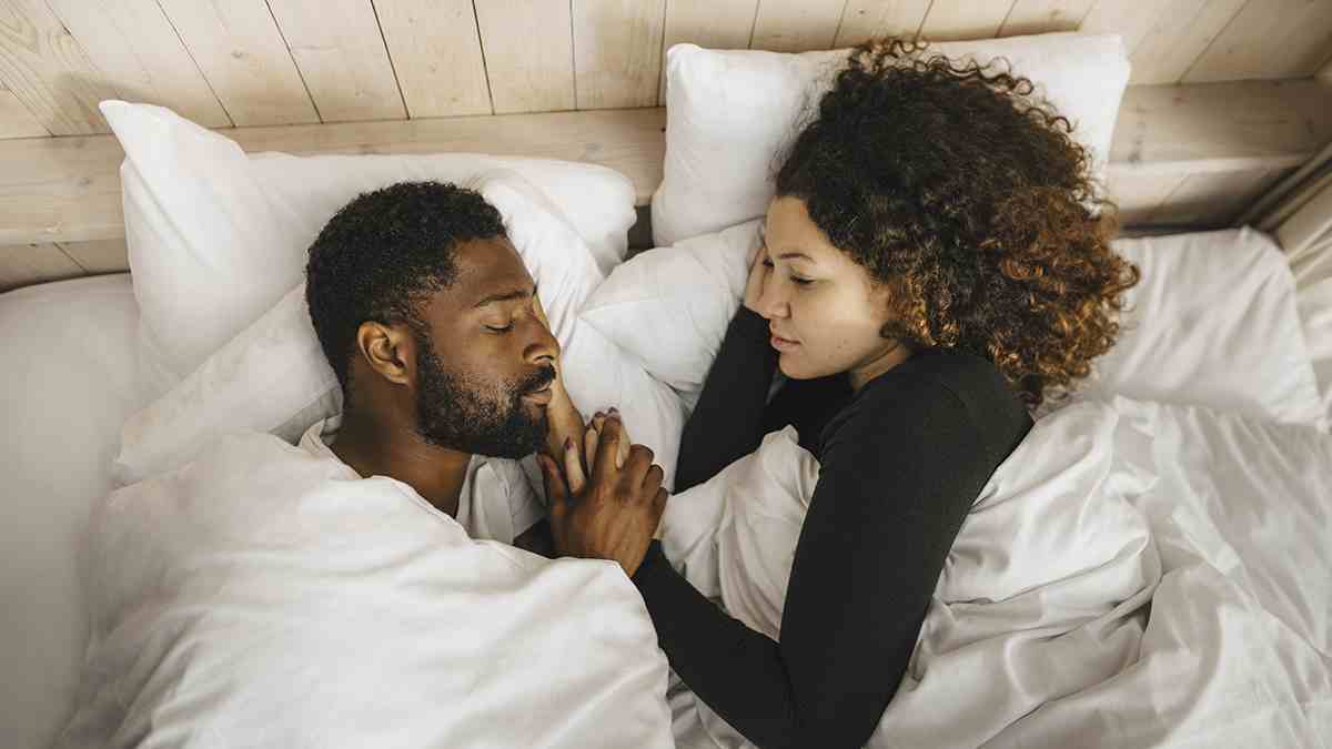 Kadın yatakta uyuyan partnerine bakıyor