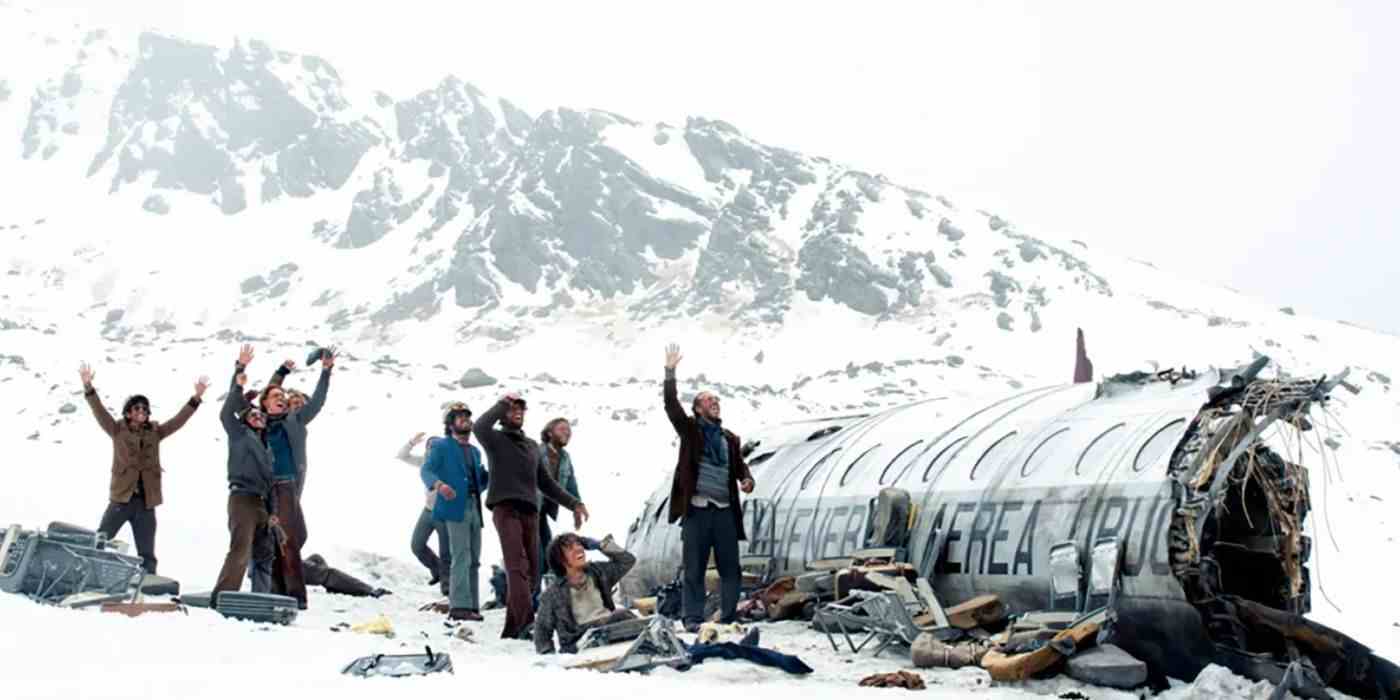 Hayatta kalan bir grup, Kar Topluluğu'nda And Dağları'nda düşen bir uçağın gövdesine kollarını kaldırıyor.