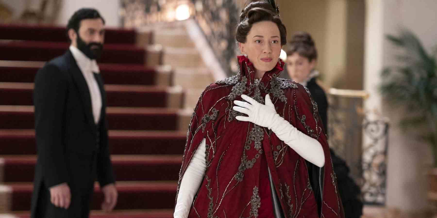 Carrie Coon, The Gilded Age'de işlemeli kırmızı bir pelerin giyen Bertha rolünde