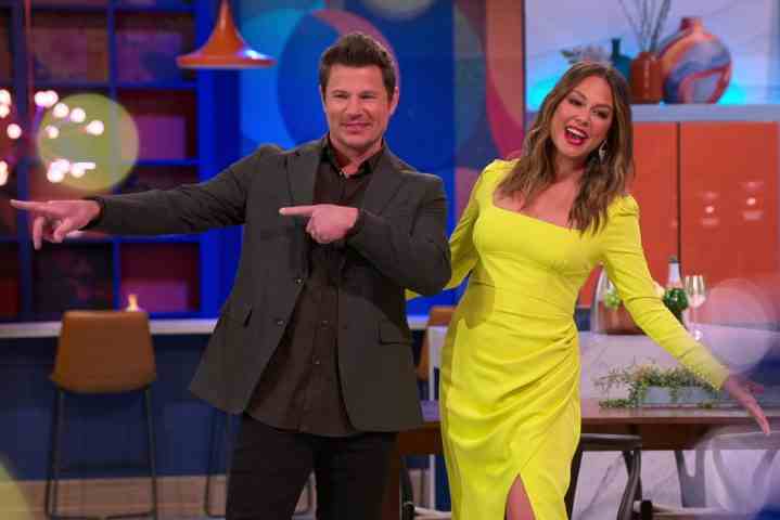 Nick Lachey, Vanessa Lachey'nin yanında duruyor ve işaret edip poz veriyor.