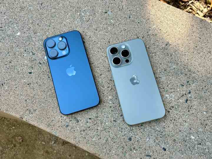 Mavi Titanyum (solda) ve Natural Titanium iPhone 15 Pro'lar beton bir bankta.
