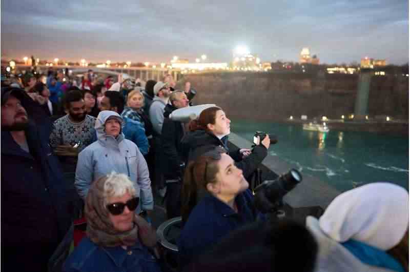 Kanada'nın Niagara Şelalesi'nde günün ilerleyen saatlerinde bölgeden geçmesi beklenen tam tutulmaya hazırlanırken insanlar gökyüzüne bakıyor.