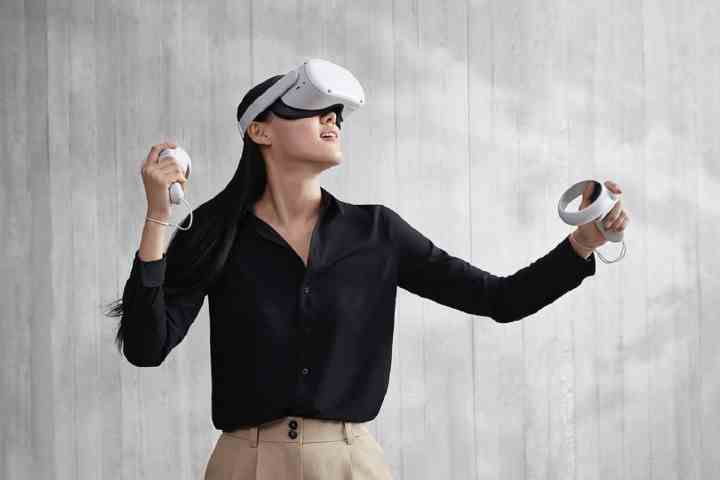 Gri bir arka planın önünde Oculus Quest 2 VR gözlüğü takan ve kullanan bir kişi.