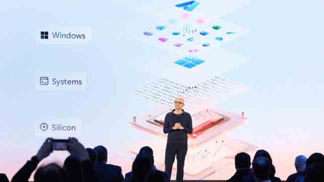 Microsoft CEO'su Satya Nadella, WIndows Systems ve Silicon isimleriyle çevrili bir sahnede duruyor